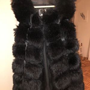 Svart fluffig pälsväst från Wenafa - Säljer en svart pälsväst från Wenafa med riktigt fluffig och voluminös look. Västen har breda, mjuka pälssektioner och är helsvart med slät insida. Perfekt för dig som vill sticka ut med en lyxig och trendig vibe.