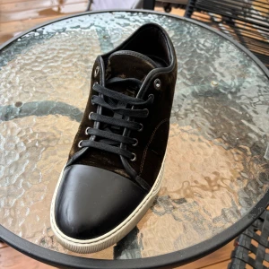 Lanvin skor - Säljer ett par svarta Lanvin sneakers med ovandel i lyxig mocka och tå i svart skinn. Skorna har vita gummisulor och svarta skosnören. Klassisk och stilren design som passar till det mesta. Perfekta för dig som gillar premium streetwear. Använda och köpta från en vän för 2000. Har väldigt små rep/hål vid sidan om skon men inget som är så märkvärdigt. Priset är ej hugget i sten, så det är bara att komma med förslag! 😊
