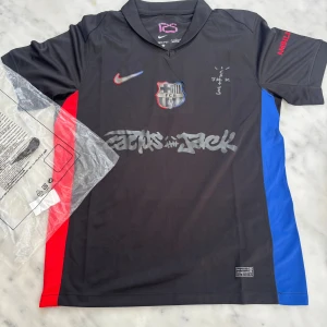 FC Barcelona x Nike svart fotbollströja S - Säljer en svart FC Barcelona fotbollströja från Nike i Dri-FIT-material. Tröjan har korta ärmar, klubbmärke på bröstet, grafiska tryck och detaljer i rött och blått på sidorna. UNHCR-logga på ryggen och specialdesignad front. Perfekt för dig som älskar fotboll och streetstyle.