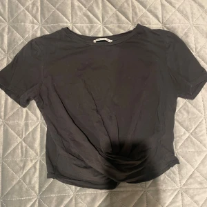 Svart croppad topp från Zara Trafaluc - Svart croppad topp från Zara Trafaluc med rund hals och korta ärmar. Enkel och stilren design i mjuk bomull som passar perfekt till jeans eller kjol. Snyggt basic-plagg för dig som gillar minimalistisk stil. Toppen har som en Knut längst ner.🖤