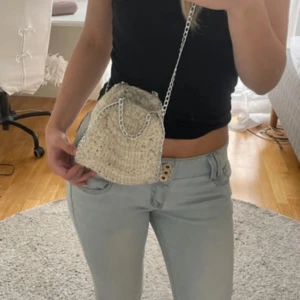 Beige stickad axelväska med kedja - Supersöt beige stickad axelväska med chunky virkat mönster och silvrig kedja som axelrem. Perfekt storlek för mobilen och det viktigaste. Väskan är smutsig men jag tror att man kan tvätta den 