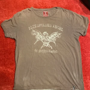 Brun t-shirt Jack & Jones med tryck - Cool brun t-shirt från Jack & Jones med vintagekänsla och tryck av en bevingad ängel och texten 'Blindfolded Angel' på bröstet. Skön passform och tillverkad i mjuk bomull. Perfekt för dig som gillar unika tryck och streetstyle.