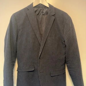Mörkblå kostym i linne - Snygg tvådelad kostym i mörkblått med klassisk kavaj och matchande byxor från Jack and Jones. Kavajen har smala slag, två fickor med lock och en bröstficka. Byxorna har raka ben och sidofickor. Tillverkad i svalt linne, perfekt för en stilren look. Skriv gärna för fler bilder eller om du har någon fråga :)