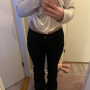 Svarta bootcut jeans från Nelly  - Snygga svarta jeans med bootcut passform och klassisk femficksdesign. Jeansen har low waist midja och är tillverkade i ett mjukt bomullsmaterial med stretch. Bakfickorna har en cool zigzag-detalj som ger extra stilpoäng. Perfekta för dig som gillar en tidlös look.