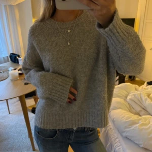 Zara tröja - Mysig grå stickad tröja från zara med rund hals och breda ribbade muddar vid ärmslut och nederkant. Modellen är loose fit och har långa ärmar, perfekt att slänga på sig när det är kyligt ute. Passar lika bra till jeans som till kjol.