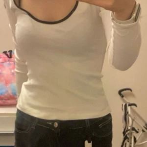 Vit långärmad topp från Amisu - Säljer en vit långärmad topp från Amisu i storlek S. Toppen har en snygg kontrastkant i svart runt den rundade halsen och är figurnära i passformen. Materialet är mjukt och stretchigt, perfekt för en clean och enkel look.