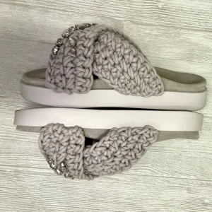 Grå/Beige stickade sandaler från Inuikii - Snygga sandaler från Inuikii i beige/grå med breda stickade band och stora glittriga stenar som detalj. Skorna har en platt vit sula och öppen tå, perfekt för en chill och trendig look. Materialet är stickat och sulan är i syntet. Köpte fel storlek, enbart använda en gång.