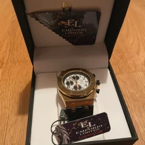 Emporio klocka - Har bara en defekt och det är en rött streck i baksidan  Reference Roma Collection cod.3501 I PT/729.00 Movement Chronometer Gender Unisex CASE Material Alloy Color Gold Diameter 40 mm Crystal Mineral glass Dial color White Function Time STRAP Band material Genuine leather Color Black Height from 25mm to 15MM Closure Buckle