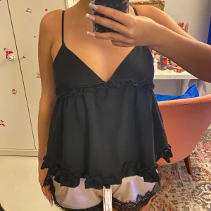 Svart volang topp - Svart topp me v ringning och volanger från shien därav billigt pris. Bandet på ensa sidan har lossnat men lagats (se bild 4) Jättesöt och önskar att den kom mer till användning men tyvärr gör den inte det! Skriv om du undrar något❤️