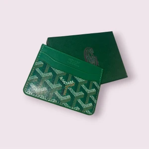 Grön plånbok med mönster - Snygg grön plånbok  med ikoniskt grafiskt mönster i vitt och brunt. Slimmad design med flera fack för kort, perfekt att ha i fickan eller väskan. Kommer i original ask med logga. Lyxig och stilren accessoar. Har även andra färger så kolla in min profil för annat! Pris går ner vid snabb affär!