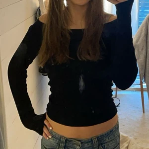 Svart offshoulder långärmad tröja - Säljer en svart långärmad tröja med offshoulder-design. Tröjan är tight och har en croppad passform som visar midjan. Perfekt för dig som gillar en stilren och trendig look.
