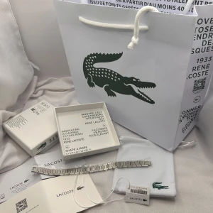 lacoste armband  - Lacoste Bracelet (Silver)  • Condition: Brand new – no scratches, no damage • Color: Silver • Material: Stainless Steel • Length: 19 cm (adjustable – like a watch)  Included: Everything shown in the ad ✓ Original Lacoste box ✓ Lacoste bracelet ✓ Dust bag ✓ Lacoste shopping bag ✓ Authenticity papers ✓ Digital receipt (available and shown in the ad)  If you have any questions, feel free to ask!