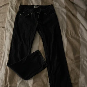 Svarta jeans från 157, straight fit - Svarta jeans från 157 med klassisk femficksdesign och raka ben. Jeansen har silverfärgade nitar och knappar, samt tydliga sömmar. Materialet är robust denim som ger en clean och tidlös look. Perfekt för dig som gillar enkel och stilren vibe.