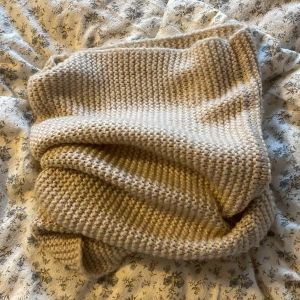 Beige stickad halsduk från H&M - Säljer en mysig och tjock beige stickad halsduk från H&M. Den här ät enkel att matcha till outfits pga dens neutrala färg. Gosigt material, inte sticksigt.
