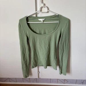 Ljusgrön långärmad topp från H&M - Säljer en ljusgrön långärmad topp från H&M i storlek XS. Toppen har en rundad, lite djupare halsringning och är tillverkad i mjuk bomull. Enkel och clean design som är lätt att matcha med olika outfits.