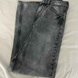 Grå straight jeans med dragkedja - Snygga grå jeans med tvättad look och klassisk femficksdesign. Modellen är straight och har normal passform, med dragkedja och knapp framtill. Perfekt för dig som gillar en enkel men cool stil. Materialet är robust jeans och färgen är mörkgrå.