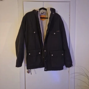 Svart parkajacka från Fjällräven G-1000 - Parkajacka från Fjällräven i svart G-1000 material med mysigt teddyfoder. Jackan har flera stora fickor med tryckknappa och en innerficka. Fjällräven-märke på ärmen. Perfekt för kalla dagar🥰                        Original pris 4 000
