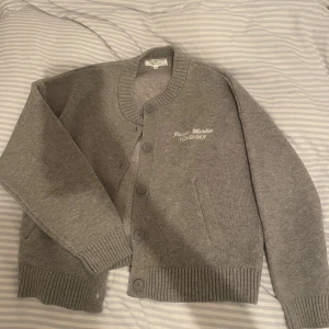 Stickad kofta med tryck  - Grå stickad kofta med tryck på ryggen, storlek S! Använd någon enstaka gång