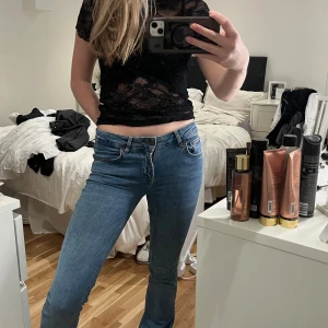 Blå bootcut jeans låg midja - Snygga blå jeans med bootcut och låg midja. Klassisk femficksmodell med dragkedja och knapp framtill. Jeansen har en rak passform över låren och utsvängda ben, vilket ger en cool siluett. Perfekta för dig som gillar en avslappnad och trendig look. (Liten lagning över bakfickan men som inte märks då man bär de)