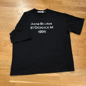 Svart Acne Studios t-shirt Stockholm - Säljer denna Acne-tröja i storlek S, men den känns mer som en M. Jag är 190 cm och den sitter bra, så om du brukar ha M kommer den passa perfekt. I fint skick Gärna skriv en dm om du är intresserad.