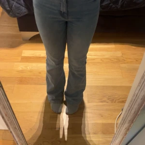 Utsvängda ljusblå jeans med hög midja - Snygga ljusblå jeans som är utsvängda och har hög midja. Jeansen har klassisk femficksdesign, dragkedja och knapp framtill. Materialet är jeans med en mjuk och skön känsla. Passformen är normal och benen är lätt utsvängda.