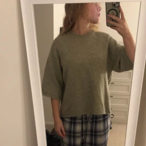 Olivgrön oversized stickad tröja - Olivgrön stickad tröja med oversized passform och breda, lite kortare ärmar. Enkel och stilren design utan synliga detaljer eller mönster. Perfekt för lager-på-lager och chill dagar.