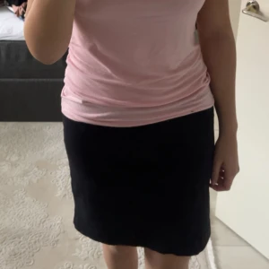 Svart enkel kortkjol - Säljer en svart, stilren kortkjol med rak passform. Kjolen är enfärgad och har en klassisk design utan synliga detaljer eller mönster. Perfekt för dig som gillar minimalistisk stil och vill ha en basic kjol i garderoben.