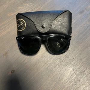  Ray-Ban Boyfriends  - Snygga svarta Ray-Ban boyfriend solglasögon med klassisk rektangulär form och polariserade mörka linser. Bågarna är tillverkade i blank svart plast och har Ray-Ban-loggan på båda sidor. Medföljer original svart fodral.