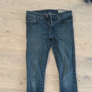Diesel Belther skinny jeans blå - Snygga blå Diesel Belther jeans med skinny passform och klassisk femficksdesign. Jeansen har regular midja, smal siluett och coola slitningar. Materialet är mjukt denim med stretch för extra komfort. Perfekt för dig som gillar en modern och stilren look.