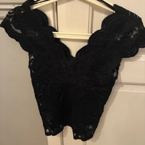 Svart spetsblus med v-ringning - Säljer en svart festtopp i spets. Trendig i ett genomskinligt material. Passar perfekt till fest eller på sommaren! Köparen står för frakt!