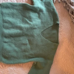 Grön stickad v-ringad tröja - Mysig grön stickad tröja med v-ringning både fram och bak. Tröjan har lång ärm och är ribbstickad för en snygg struktur. Perfekt för lager-på-lager och chill dagar.