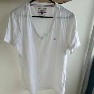 Vit v-ringad t-shirt Tommy Hilfiger - Vit t-shirt från Hilfiger med v-ringning och liten broderad logga på bröstet. Klassisk basic T-shirt