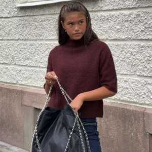 Vinröd stickad croppad tröja - Mysig vinröd stickad tröja med croppad passform och halvpolo. Tröjan har halvkort ärm och är perfekt för lager-på-lager. Mjuk och fluffig känsla, passar dig som gillar en chill men ändå trendig stil.