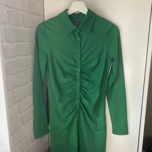 Klänning - Fin grön klänning med klabbar hela vägen som går att knäppa upp. Jätte fint till jul eller andra högtider, eller bara ha som varfagsklänning. Storlek s / m