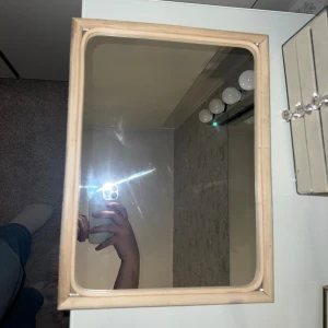 Mirror Light Bamboo - Stilren spegel med ljus bamburam från Into the Green. Spegeln är i gott skick. Perfekt för sminkbord eller hall. Enkel att hänga upp tack vare fäste på baksidan. Modern och naturlig design.