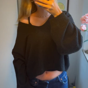 Svart croppad stickad tröja - Svart, croppad stickad tröja med loose passform och lång ärm. Tröjan har en offshoulder-look och är perfekt för dig som gillar en avslappnad och trendig stil. Enkel att matcha med jeans eller kjol. Tröjan har noppror men tycker ändå den är värd att sälja 🙈💕💕