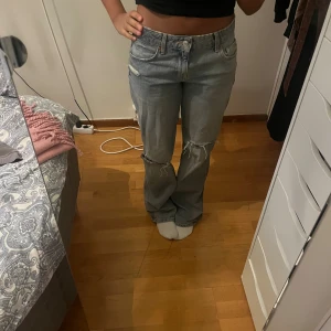 Lågmidjade jeans från Zara  - Säljer ett par lågmidjade ljusblå jeans med raka ben och snygga slitningar vid knäna. De är köpta på Zara nyligen i mycket bra skick! 