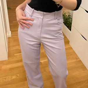 Ljuslila läder wide byxor från Zara - Säljer ett par ljuslila läder (konstläder) byxor från Zara i storlek S. Byxorna har hög midja, raka ben med wide fit och klassisk femficksdesign. Materialet är syntet med en skinnliknande finish som ger en cool vibe. Perfekt för dig som vill sticka ut med färg.