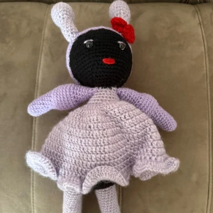 Ljuslila virkad klänning med volang - Supersöt ljuslila virkad liten docka med klänning, perfekt för dig som gillar unika och handgjorda söta dockor. Klänningen har en rundad form och är stickad i mjukt garn som ger en mysig känsla. Passar dig som samlar på liknande eller som en gåva till ett barn