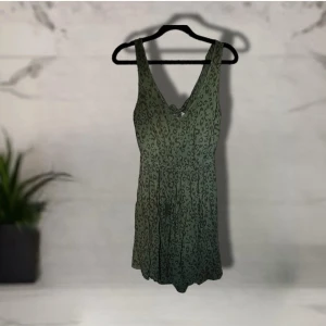Grön kortklänning med leopardmönster H&M - Snygg grön kortklänning från Divided by H&M med leopardmönster och knytning i ryggen. Klänningen har djup v-ringning både fram och bak samt ett flowy fall. Perfekt för dig som gillar djurprint och vill ha en cool sommarklänning. Fickor på båda sidorna.