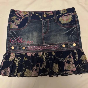 Jeanskjol med volang - Supersöt kort jeanskjol med volangkantoch broderi. Snygga fickor både fram och bak. Nya