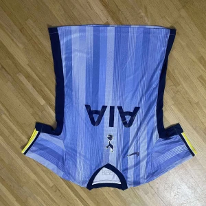 Tottenham blå bortatröja Nike - Snygg Tottenham Hotspur bortatröja från Nike i olika blå nyanser med vertikala ränder. Tröjan har korta ärmar, mörkblå detaljer på sidorna och gula inslag vid ärmsluten. Tillverkad i lätt och ventilerande material, perfekt för fotboll eller supporterliv.