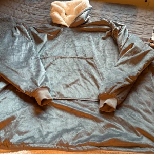 Grå oversized hoodie med teddyfoder - Supermjuk och oversized grå hoodie med fluffigt vitt teddyfoder på insidan och i huvan. Tröjan har stor känguruficka framtill, ribbade muddar och är perfekt för kalla dagar. Materialet är lent och ger en mysig känsla.