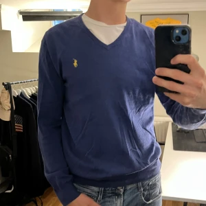 Ralph Lauren Tröja - Tjena! Säljer en stilig stickad Ralph lauren tröja, V-neck. Tröjan är i färgen blå med ett guldmärke. Tröjan är i skicket 7/10, har haft ett litet hål som är fixat, syns knappt annars är den vändigt fin. Tröjan är perfekt nu till hösten🍁 nypris runt 2000 kr Hör av dig vid funderingar🙌