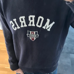 Stickad Morris tröja - Mörkblå stickad tröja från Morris med broderad logga och emblem på bröstet. Tröjan har rund hals, ribbade muddar och  långärmad. Perfekt för dig som gillar klassisk stil. Priset kan diskuteras såklart