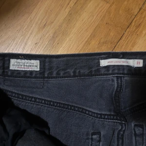 Levi's High Loose Taper jeans svart - Svarta Levi's Premium High Loose Taper jeans med hög midja och avsmalnande ben. Klassisk femficksmodell i mjuk denim med snygg tvätt och diskret Levi's-märke på bakfickan. Perfekt för dig som gillar en loose fit med modern siluett. Storlek: W31 L29. Pris går att diskutera 