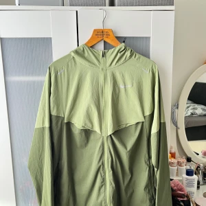 Nike running jacket repel UV windbreaker / vindjacka - Jätte fin windbreaker / löparjacka Passar perfekt som vindjacka inför hösten Denna Nike modellen är slutsåld överallt  Mörkgrön / grön färg med lime blandning Storlek XL Går att packa ihop enkelt med hjälp av fickan på sista bilden Skicka meddelande vid några funderingar Kolla gärna även in mina andra annonser