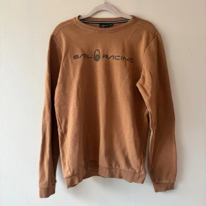 Sail Racing sweatshirt i bomull - Säljer en brun sweatshirt från Sail Racing med svart logga framtill. Nypris 599kr, fint skick! Storlek 170.
