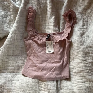 Rosa ribbad linnetopp med volang - Supersöt ljusrosa linnetopp från hm med ribbad struktur och volangdetaljer längs axelbanden.❤️
