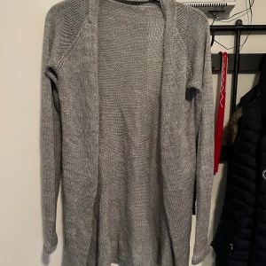Grå stickad kofta i loose fit strl: M - Mysig grå stickad kofta med lång ärm och öppen framtill. Koftan har en avslappnad loose fit och är perfekt att slänga på sig när det är kyligt. Enkel och stilren design som passar till det mesta.